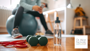 Picture of person sitting on a gym ball, resting, with weights in view